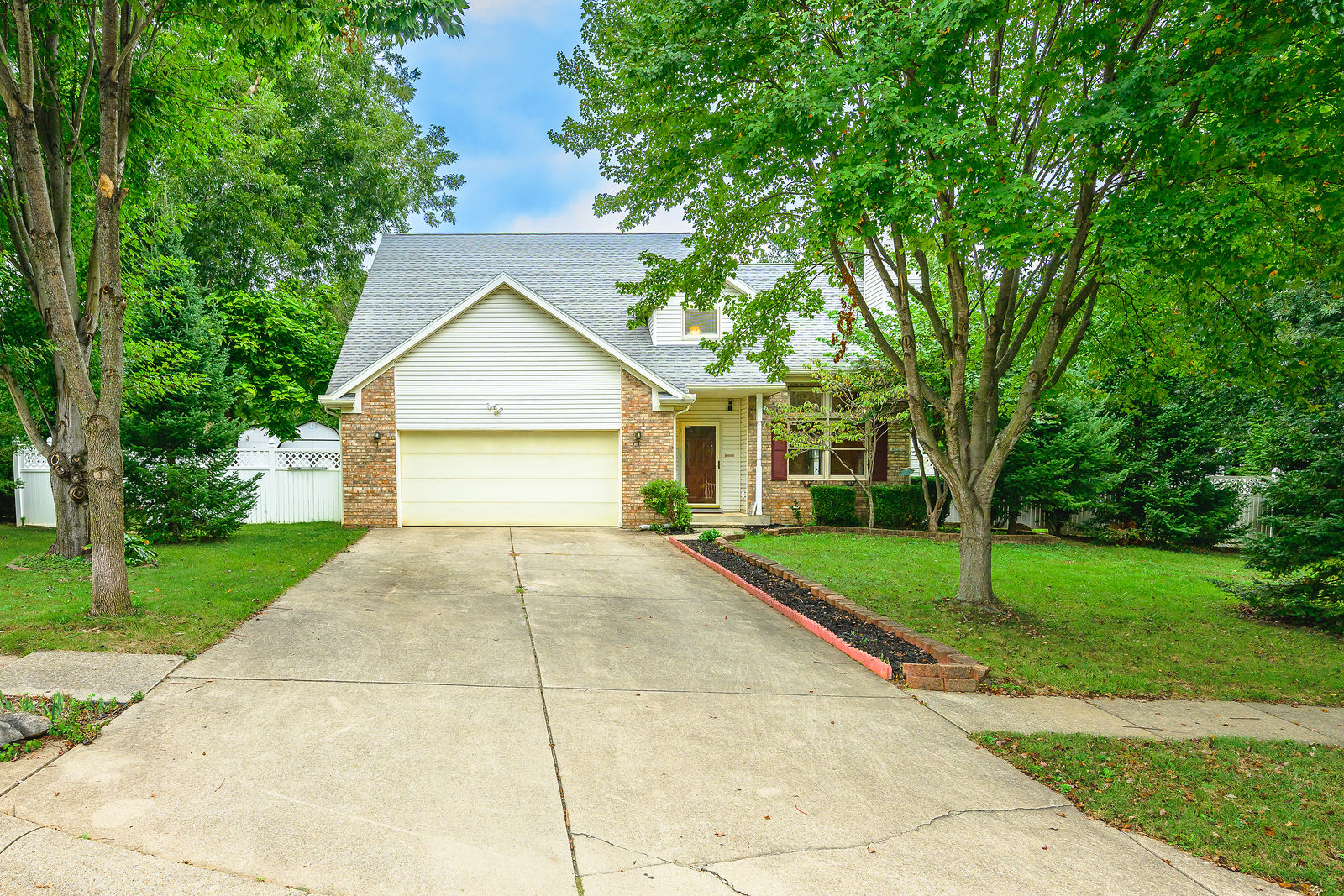 Front exterior of 600 W Cyprus Circle with two-car garage and mature trees