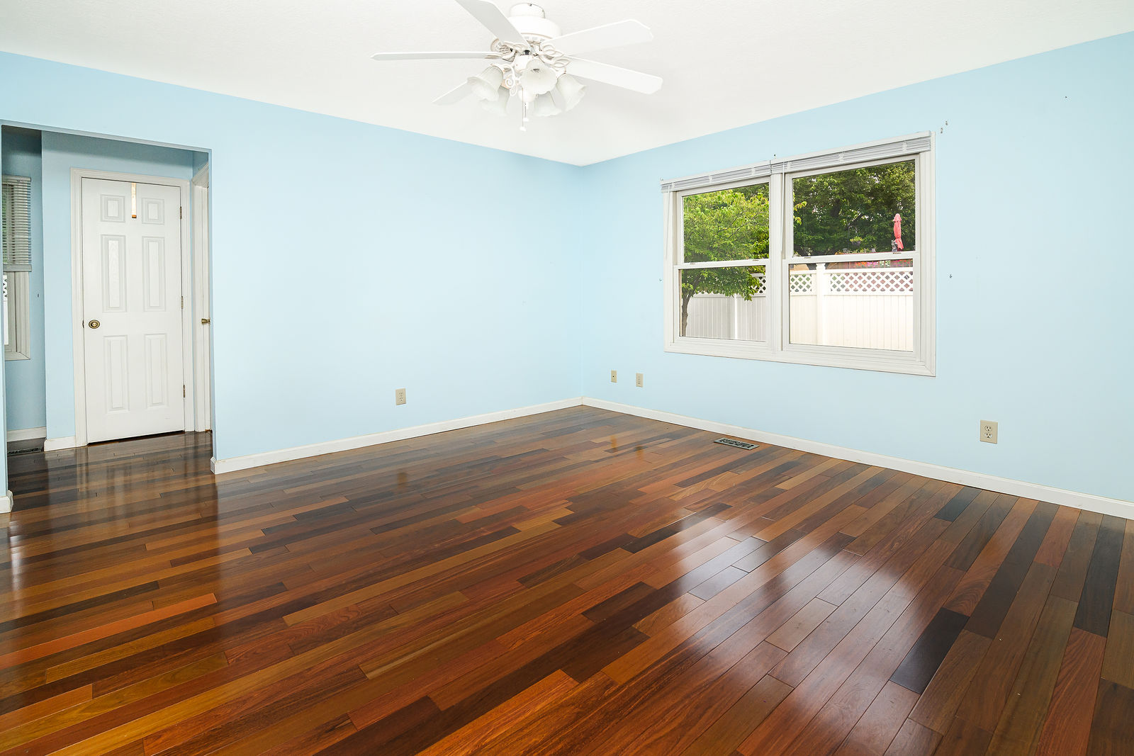Main-floor primary bedroom with hardwood floors and windows to the backyard