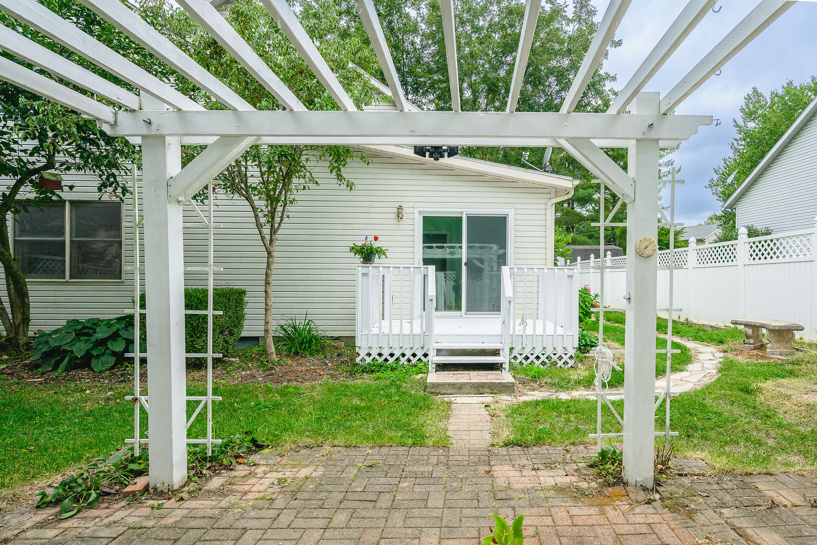 Backyard pergola, brick pavers, and deck inside a privacy fence
